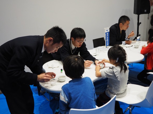 「発泡入浴剤をつくろう!」の説明をする附属高校の高田先生と谷塚さん、奥田さん