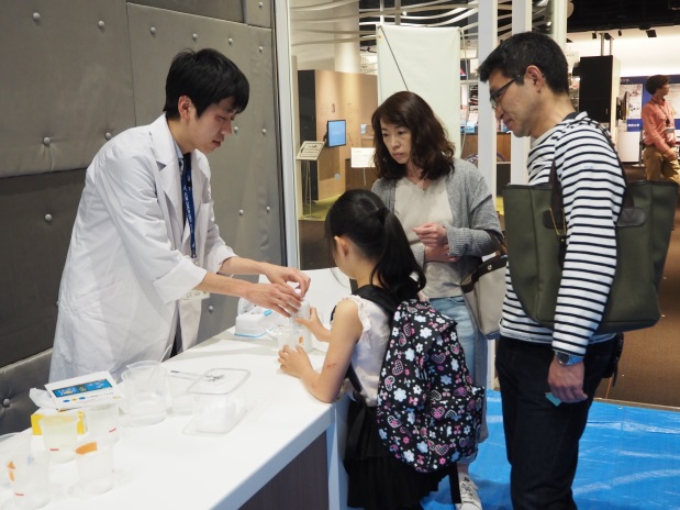 「石鹸の結晶を見てみよう」実験の説明をする、薬学部の永木英敏さん(1年次生)