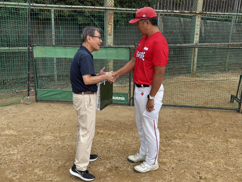 シンガポール代表チームの監督と握手する備酒学長(左)