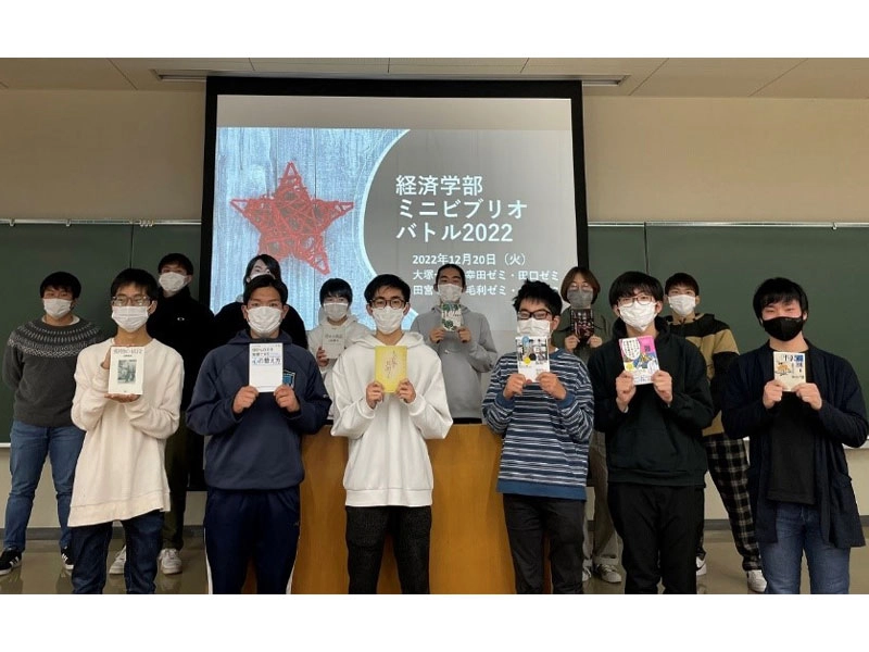 紹介した本を掲げるプレゼンテーターと、司会・質問役を務めた学生たち