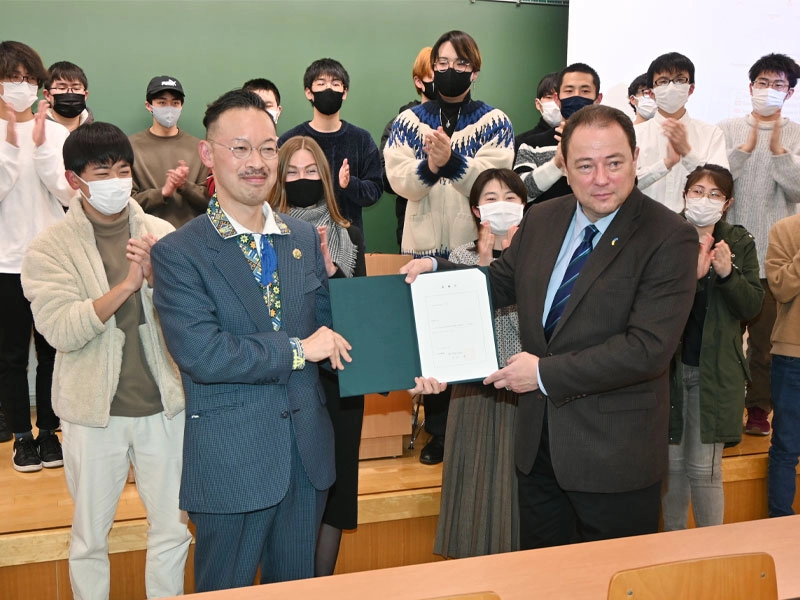 岡部所長から渡された客員教授委嘱状を見せるコルスンスキー大使
