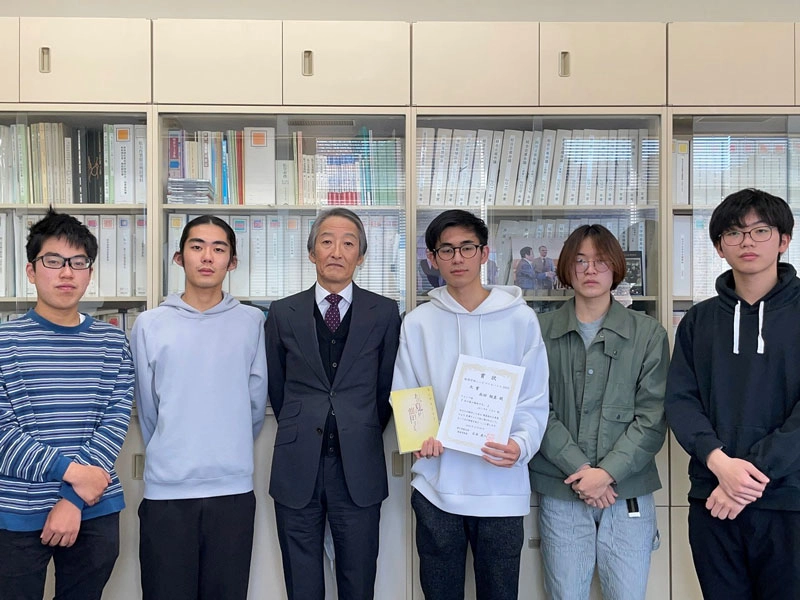 石本経済学部長(左から3人目)を囲んで記念撮影する学生たち(右隣がチャンプ本の高田さん、左隣が2位の大谷さん)