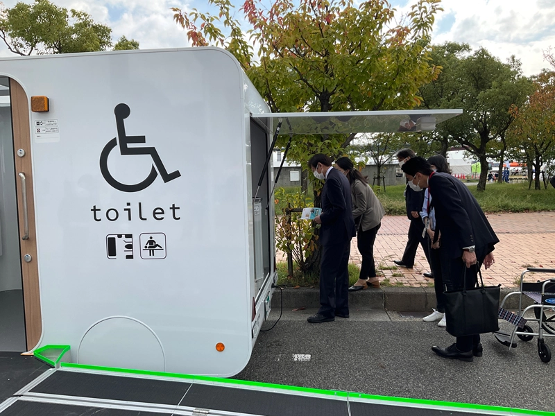 川本健太郎准教授とトヨタ自動車による屋外展示でモバイルトイレを視察する久元市長(左)