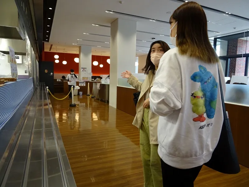 D号館のカフェ"Trattoria Fellice"を案内する市冨梓紗さん(経営学部3年次生)