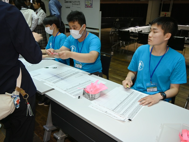 受付でリボンを渡す人文学部の学生ら