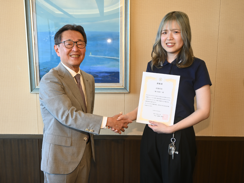 備酒学長から表彰状を渡され笑顔の三輪さん(右)