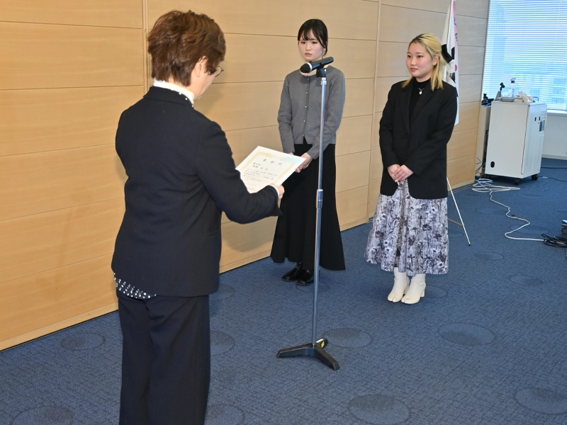 中山室長から優秀賞の表彰を受ける飯綱萌さん(左)と田中愛桜さん