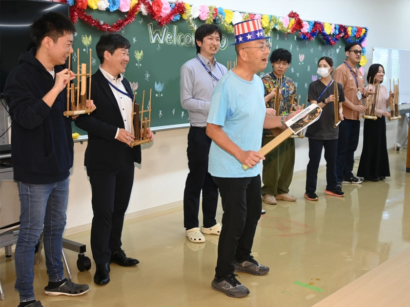 竹の楽器を演奏する白川教授(派手な帽子)ら