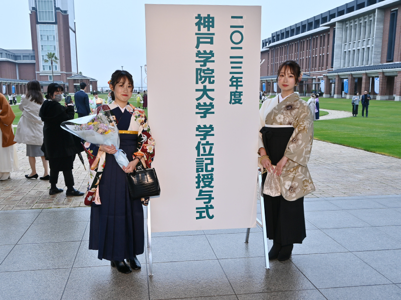 学位記授与式案内板の前で記念撮影する卒業生