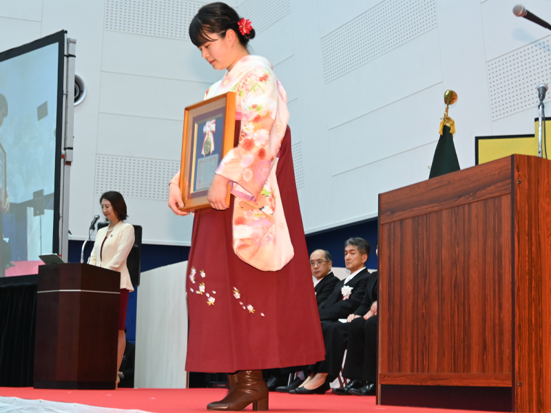 学長賞の額を受け取り、演壇から下りる現代社会学部の國松万熙さん