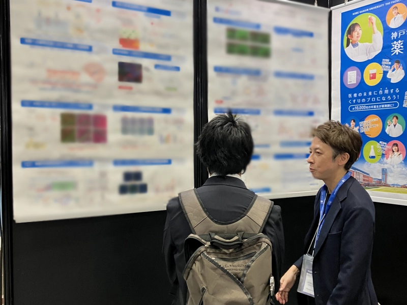 本学ブースで参加者に説明する亀井准教授