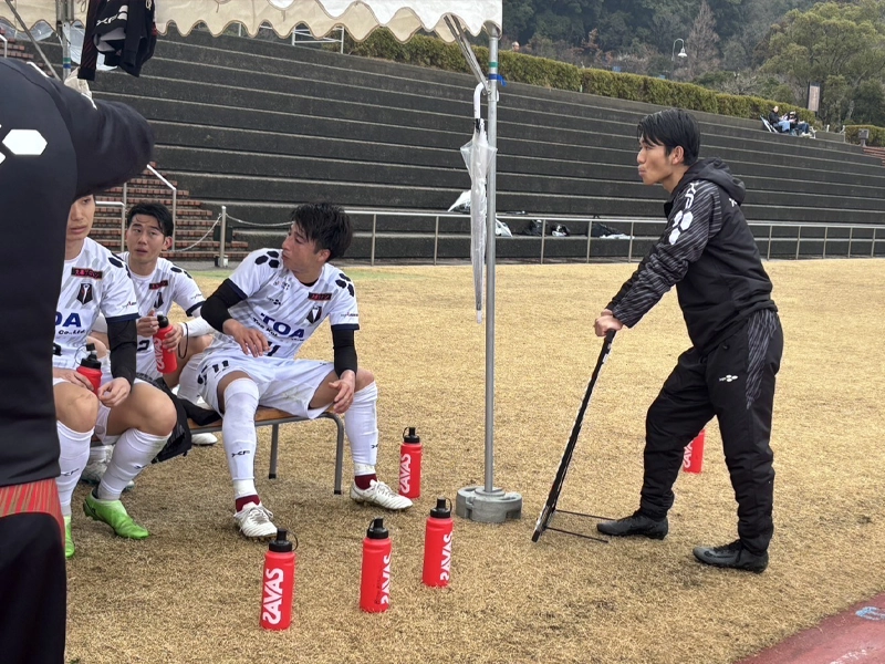 戦術ボードを手に選手と話す千知岩さん
