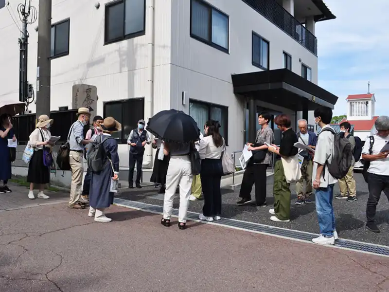 大聖寺の片隅に立つ明石市空襲の碑について矢嶋教授の説明を聞く参加者ら