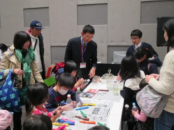 浮沈子づくりの説明を行う、附属高等学校の高田崇正先生と1年生の陸駿豪さん