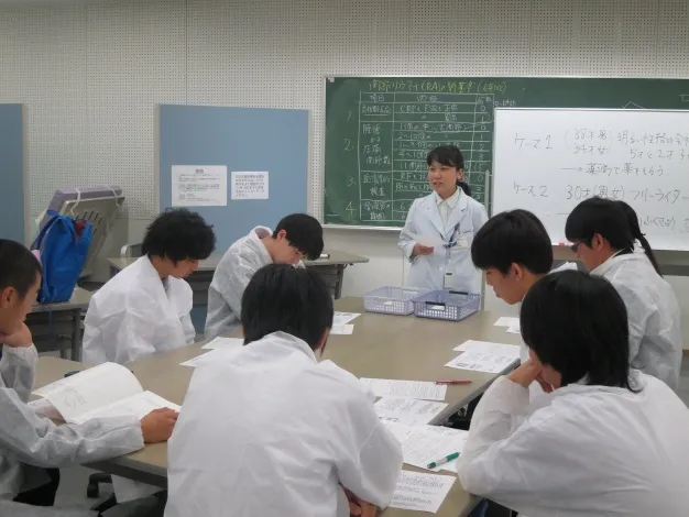 ロールプレイングで薬剤師役の生徒たちに、薬の説明と共に、患者と向き合う事について説明する上町講師