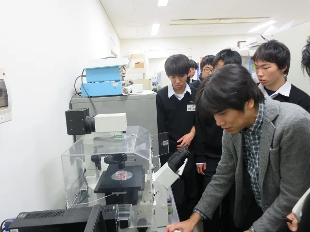 施設見学で、がん細胞の実験について説明する高橋講師