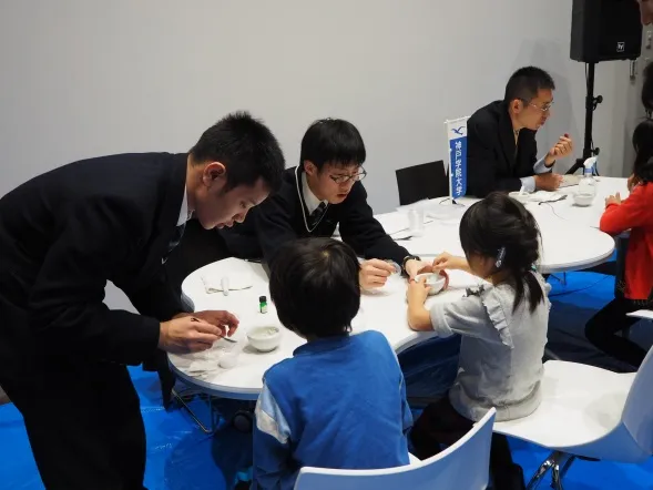 「発泡入浴剤をつくろう!」の説明をする附属高校の高田先生、谷塚さん、奥田さん