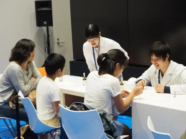 「2層のオブジェ」実験の説明をする、薬学部の髙田大貴さん(2年次生)=写真右と、大塚里彩さん(1年次生)