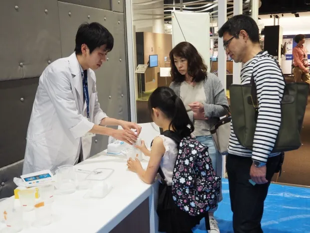 「石鹸の結晶を見てみよう」実験の説明をする、薬学部の永木英敏さん(1年次生)