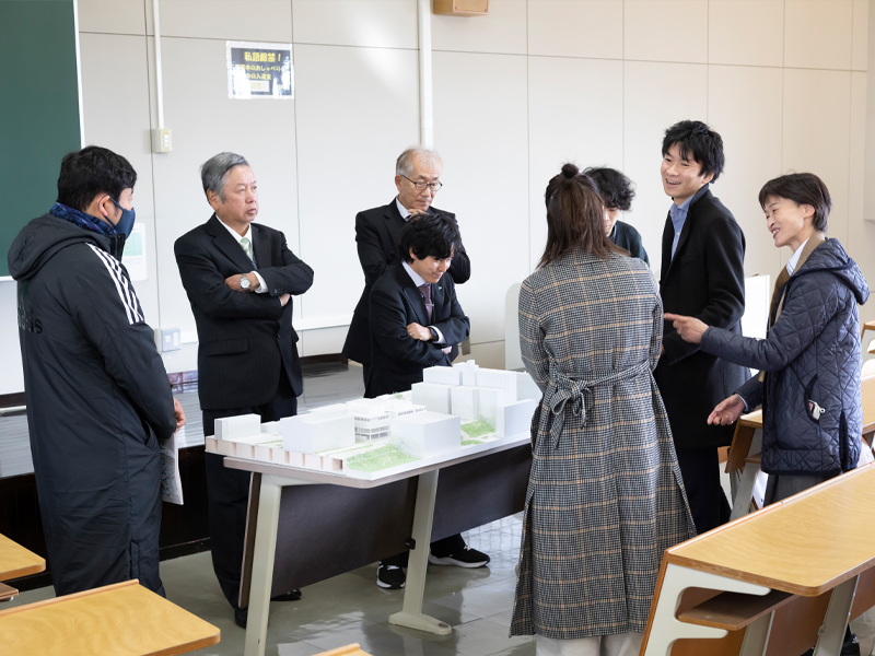 1号館の完成予定模型を囲み談笑する同窓会の人たち