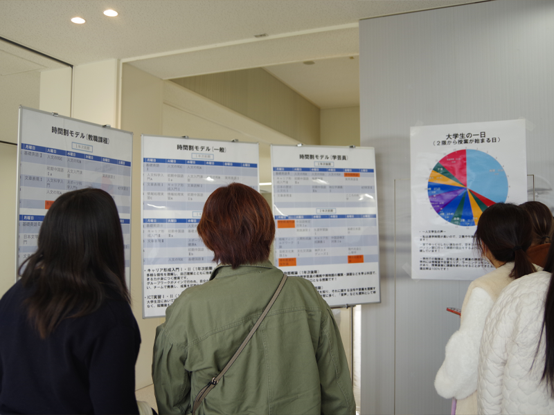 大学生の時間割や生活スケジュールの紹介パネルを見る来場者
