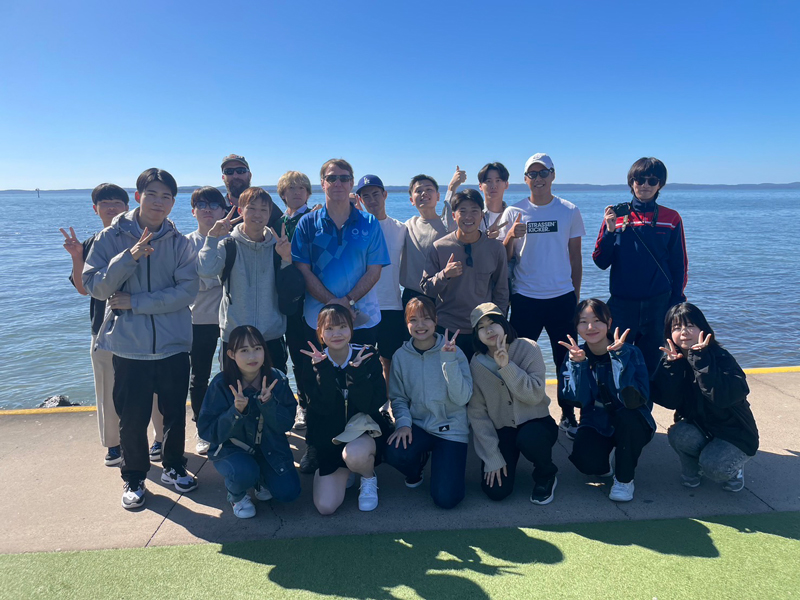 海岸で記念撮影する学生たち