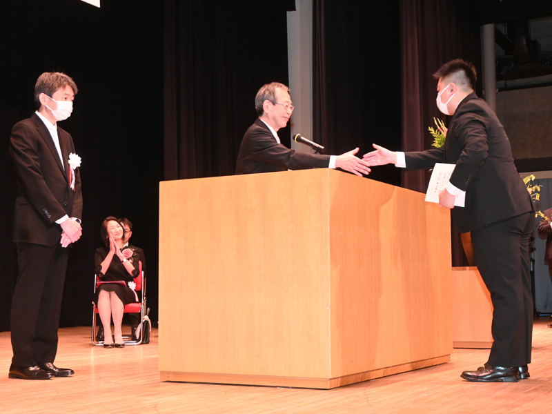 学位記を授与した学生と握手する中村学長