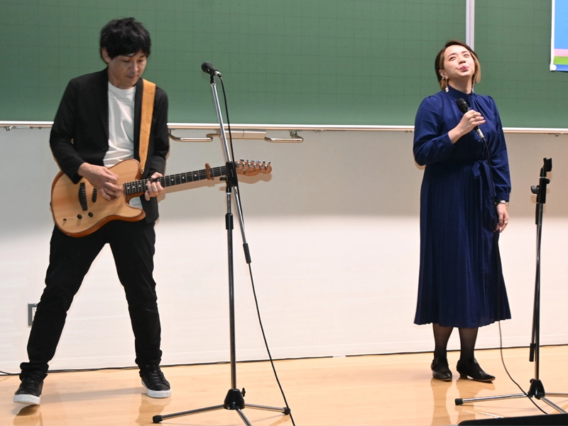 プロジェクトのテーマ曲を披露する山田明義さん(左)とアヤヲさん