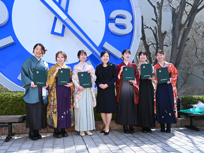大時計前で恩師を囲み記念撮影する卒業生
