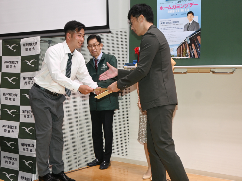 サイン色紙を矢野さんから手渡され、感激の学生（左）