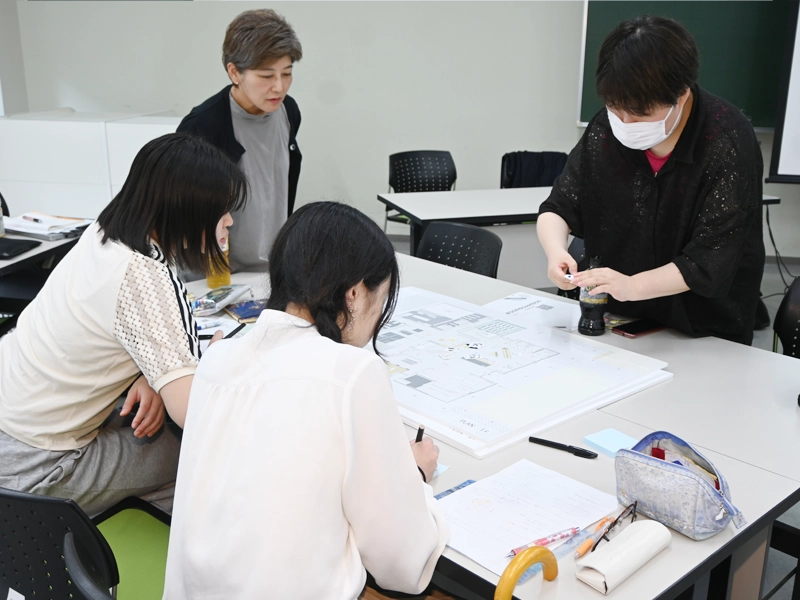 アイデアを書いた付箋を貼る学生
