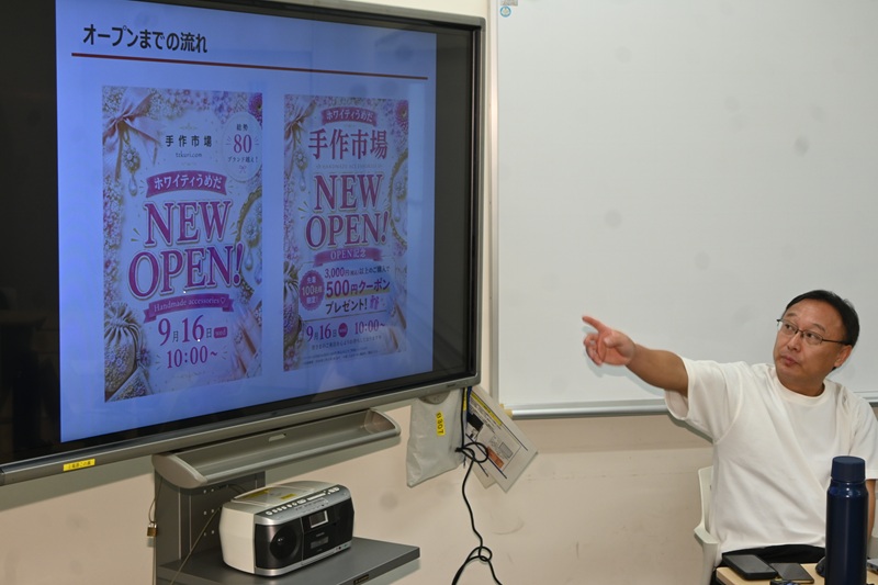 当初のポスター案(左)を見て「手作市場」の文字を大きくするデザインに改善したと話す田中さん