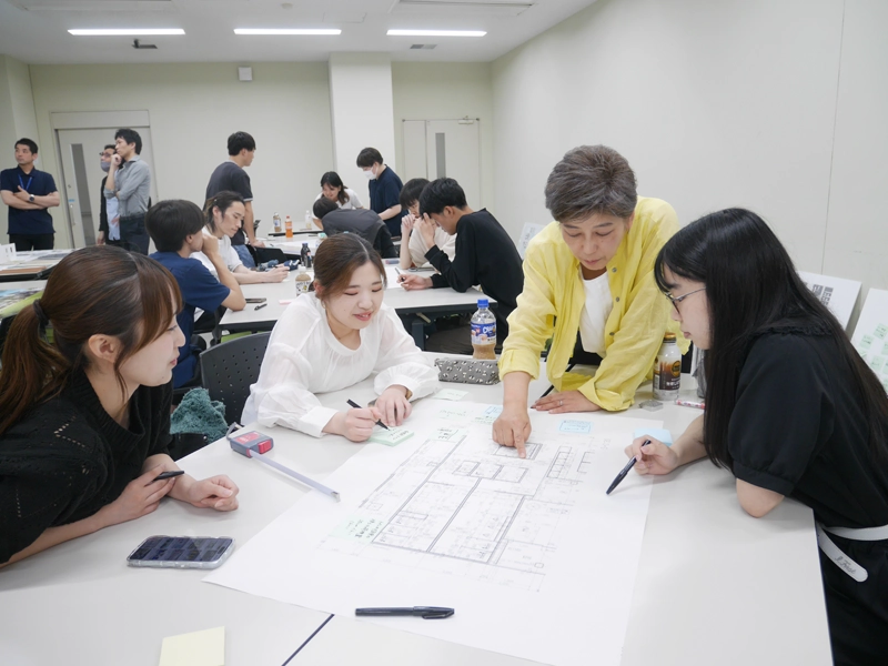設計図を見ながら話し合う糟谷教授と学生
