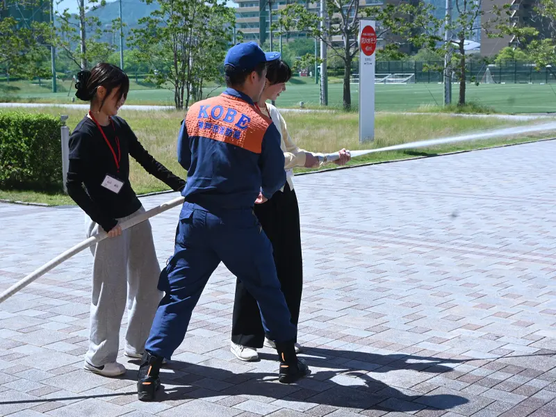 消火栓から引いたホースで放水する学生