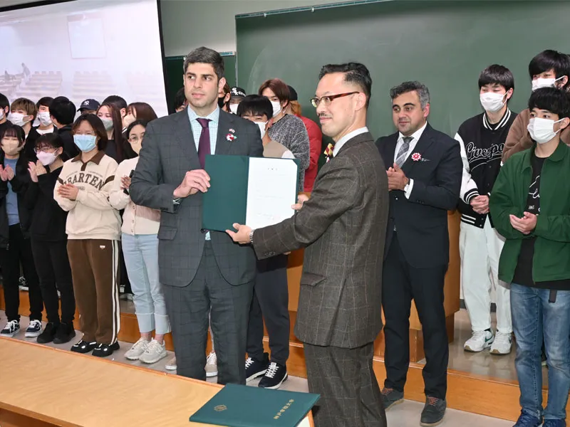 岡部国際交流センター所長から客員教授の委嘱状を受け取るレジャバ大使