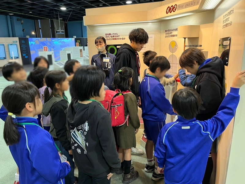 瞬発力を測る音と光のゲームを楽しむ小学生とサポートする江田ゼミ生