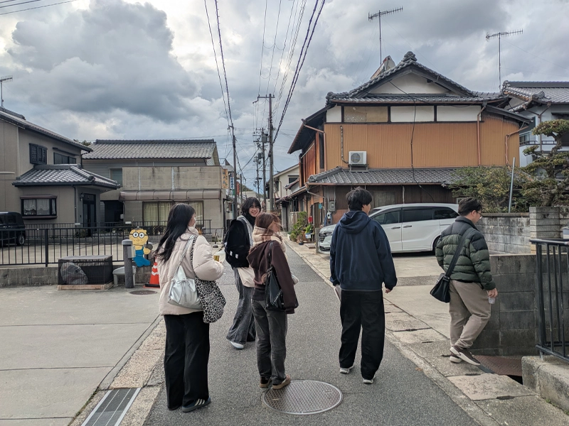 地図を片手に街並みを比較する学生ら