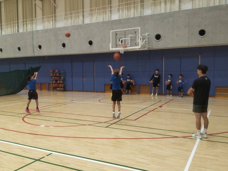 小学生のシュートを見守るバスケットボール部員