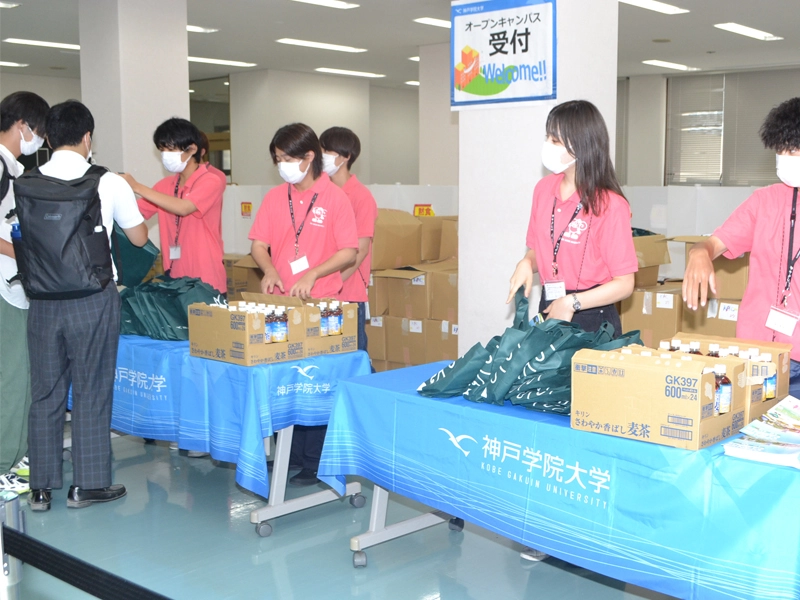 受け付けで大学名の入ったバッグやお茶を配る学生