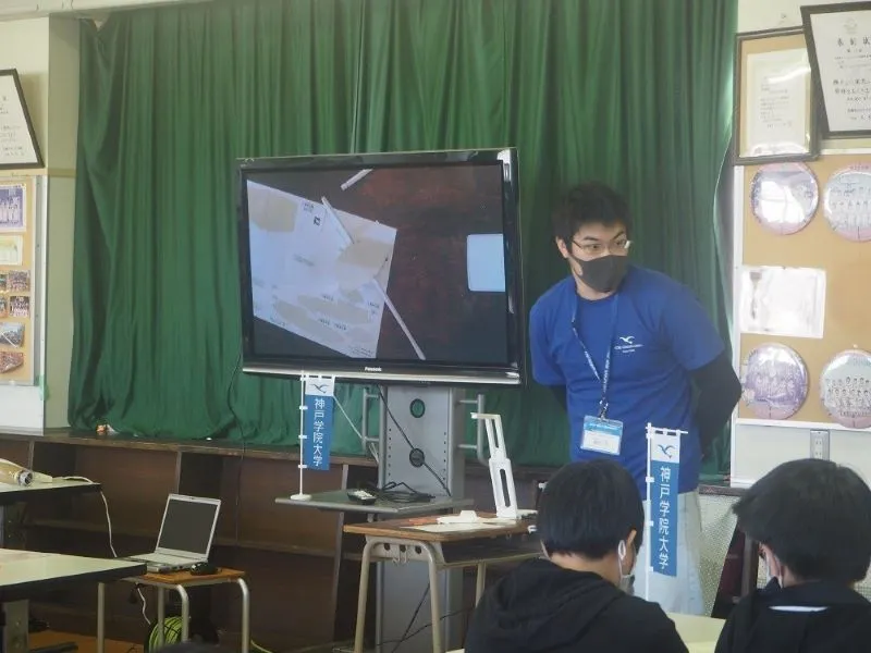 手元カメラで組立方法を教える学生スタッフ