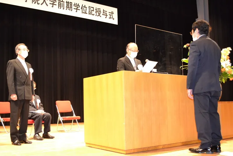 佐藤学長が読み上げる学位記の言葉を聞く卒業生
