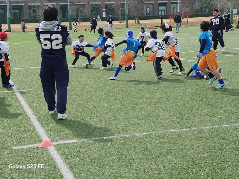 熱戦を展開する小学生と見守るアメフト部員