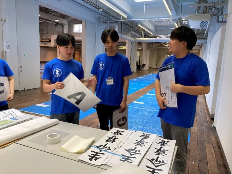 進行の手順を確認する3人の学生