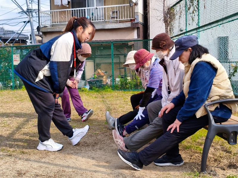 ももの裏のストレッチを指導する学生