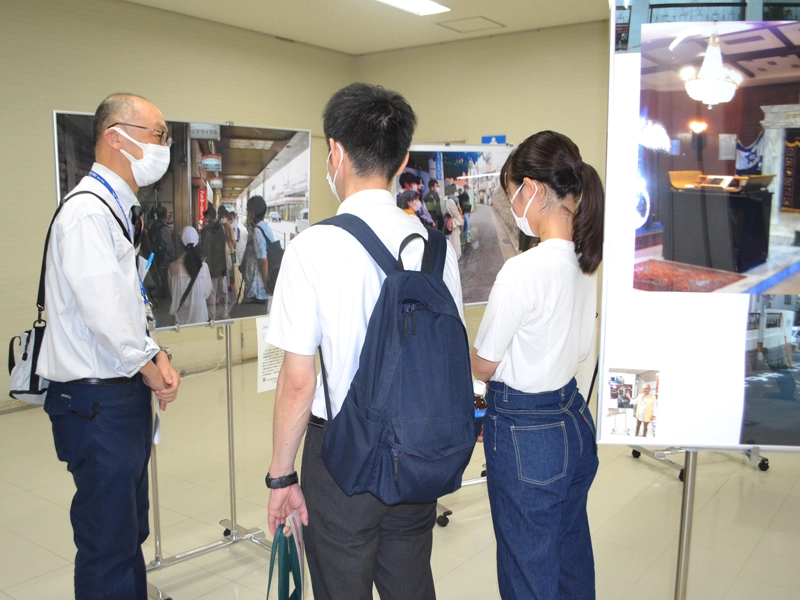 人文学部の活動を伝えるパネル写真の前で説明する矢嶋教授(左端)