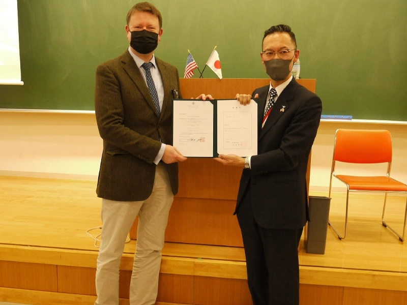 ハサウェイ領事(左)に客員教授委嘱状を渡す岡部所長
