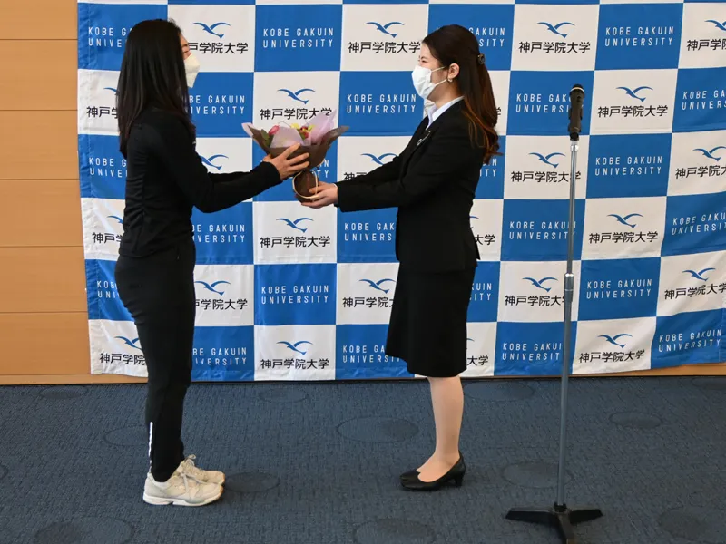 学生を代表して坂本さんに花束を手渡す体育会本部会長の中谷綾乃さん(右)