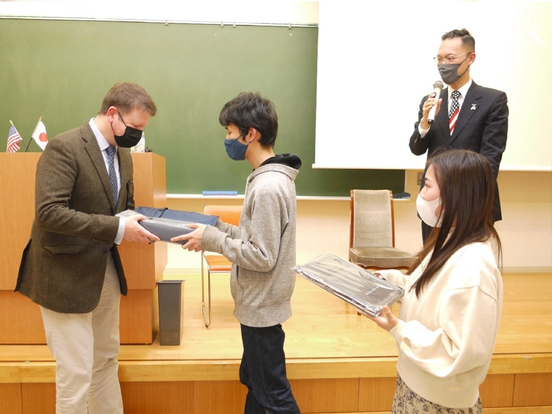 ハサウェイ領事に御礼の記念品を手渡す学生ら