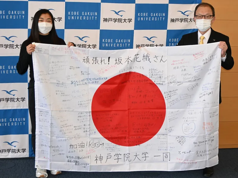 西本理事長(右)から贈呈された寄せ書きを披露する坂本さん
